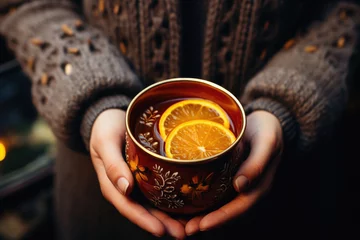 Foto op Plexiglas Female hands holding a cup of hot tea with orange and cinnamon. © Synthetica
