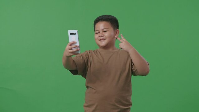 Asian Boy Make Selfie By Smartphone On Green Screen In The Studio
