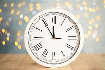 Fototapeta na wymiar Clock showing five minutes until midnight on blurred background. New Year countdown