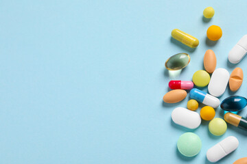 Many different pills on light blue background, flat lay. Space for text
