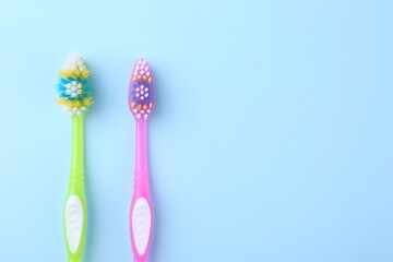 Colorful plastic toothbrushes on light blue background, flat lay. Space for text