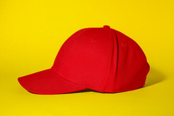 Stylish red baseball cap on yellow background
