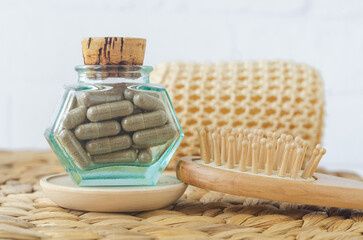 Small vintage bottle with food supplement capsules and wooden hairbrush. Natural healthcare, herbal medicine and hair treatment.
