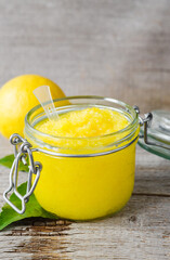 Homemade lemon scrub in a glass jar. Diy natural beauty treatment and spa recipe. Old wooden background.