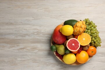 Different ripe fruits and berries on light wooden table, top view. Space for text