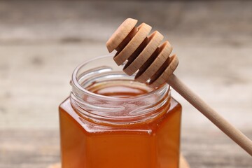 Sweet honey in jar and dipper on table, closeup