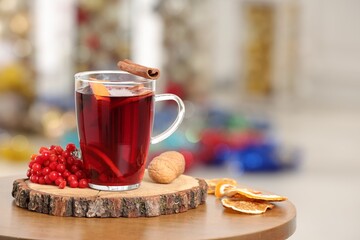 Aromatic mulled wine in glass cup on wooden table against blurred background. Space for text