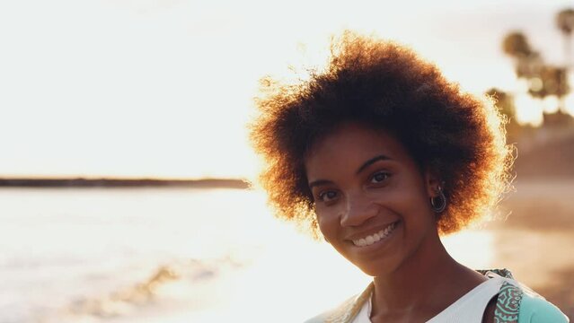 One young beautiful afro woman walking on the sand of the beach enjoying summer and having fun outdoors with sunset in the background. Portrait people vacations free time concept enjoy
