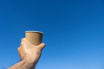 青空と紙コップを持つ男の手（30代、日本人）