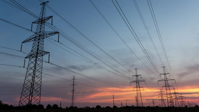 Large pylons of power lines against the background of an orange sunset, time lapse, 4k