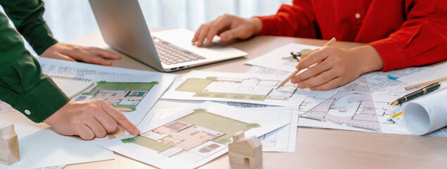 Fototapeta na wymiar A portrait of skillful architect discussing with his coworker about house construction design during using laptop. Professional engineers choose house plan carefully. Closeup. Delineation.