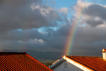 Rainbow on a cloudy day over the roofs of houses