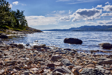 Fototapeta na wymiar Late September afternoon, a close up view of the rock strewn beach looking south west across Lachlan Bay towards Loch Fyne. Argyll