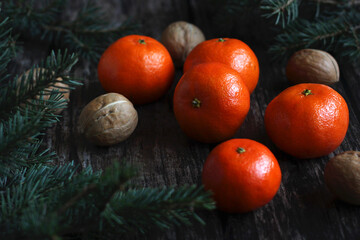 New Year's layout of tangerines, spruce branches and walnuts on a wooden background
