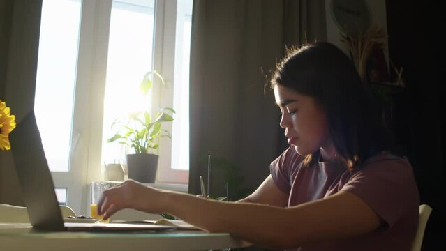 Young female student working on laptop from home