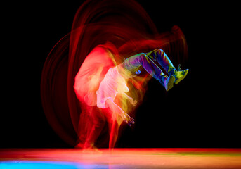 Hip-hop male dancer, athletic guy dancing in stylish outfit against black background in mixed neon...