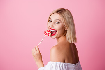 Photo of sweet excited girl dressed off shoulders outfit enjoying lollipop caramel empty space isolated pink color background