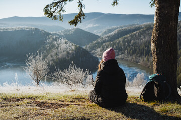 Back view of girl sitting on the background of mountain landscape in winter, meditation in nature,...