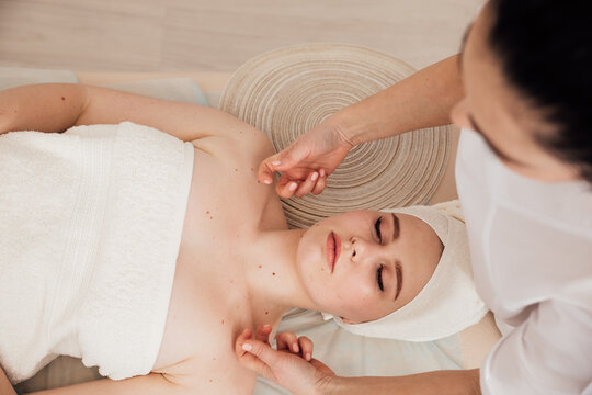 A woman beautician massages the shoulders of a client