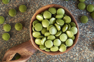 Green barley grass tablets on a wooden spoon