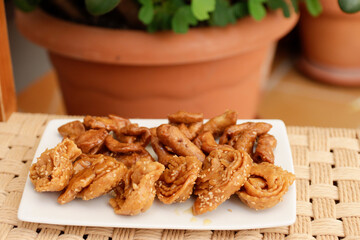 Moroccan chebakias on a white plate in a patio with plants