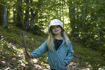 Adorable little girl hiking in the forest, spending time in the nature, outdoors experience in the countryside	