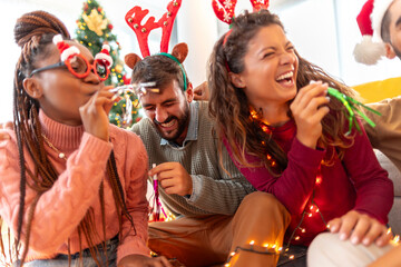 Friends blowing party whistles while celebrating Christmas at home