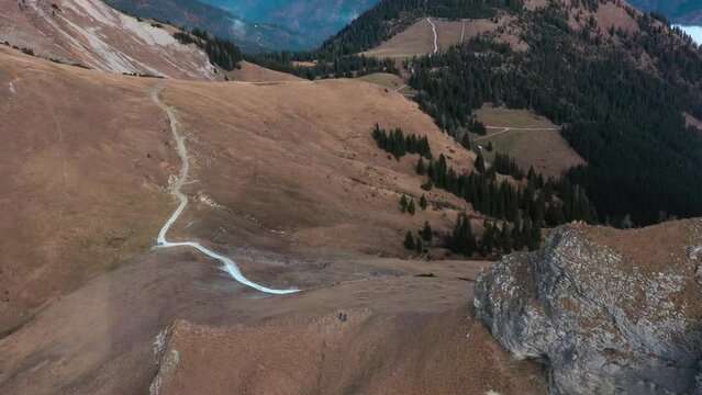 Drone footage of alpine mountain scenery with forests and mountains in the fall and two hikers on the mountain. Achensee, Tirol, Austria