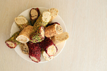 Many rolls of turkish delight with different flavors and fillings in white plate on table. Cuts of...