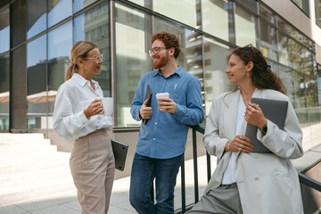 Smiling business colleagues talking and laughing during break time outside of office