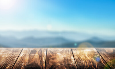  empty wooden table with a free space on the background of a landscape of mountains with sunlight....