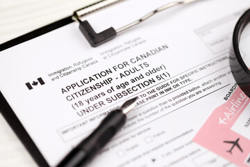 Application for Canadian citizenship for adults on A4 tablet lies on office table with pen and magnifying glass close up