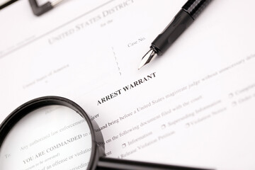 District Court Arrest Warrant court papers on A4 tablet lies on office table with pen and...