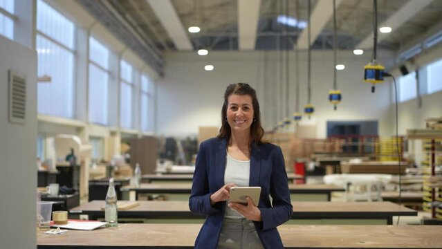 Confident businesswoman holds tablet and smiles into camera