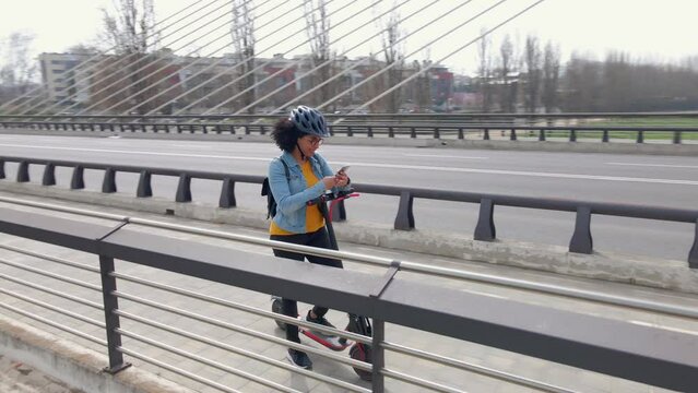 Woman with e-scooter using smartphone on bicycle lane