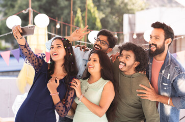 Group of Friends taking selfie on smartphone during reunion new year party gathering at evening - concept of millennial lifestyles, celebration and enjoyment