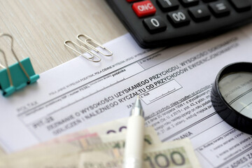 Declaration of amount of income obtained, amount of deductions made and lump sum due from recorded income, PIT-28 form on accountant table with pen and polish zloty money bills close up