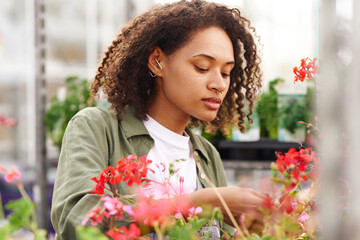 Positive female gardener takes care of plants while working in greenhouse. High quality photo