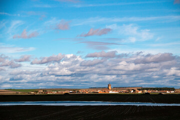 Obraz premium The village of Pajares de Adaja in Castilla y León in Spain, a view of its church, houses and crop fields