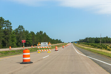 A two lane US highway with the left lane closed off with barriers and a sign saying lane closed