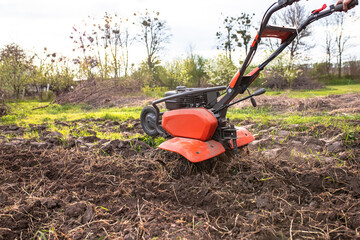 Motor cultivator with a raised front wheel and a furrow inserted into the ground during ploughing...
