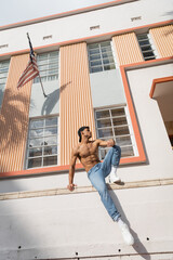 cuban man with muscular body posing in baseball cap and jeans on street in Miami in summer