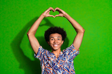 Portrait of cheerful young guy in stylish trendy jamaican shirt make love gesture using his fingers...