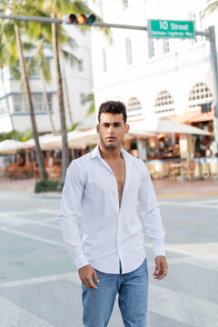 Portrait of young cuban man in jeans and white shirt looking at camera in Miami, south beach