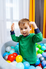 Fototapeta na wymiar A young boy playing in a ball pit. A Young Boy Having Fun in a Colorful Ball Pit