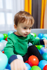 A Playful Adventure in a Colorful Ball Pit. A little boy sitting in a ball pit