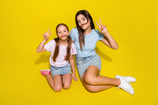 Photo of positive cheerful girls playing make grimace v sign on holiday weekends isolated over bright color background