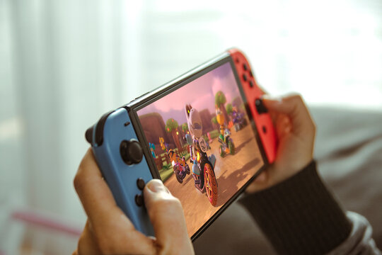 Young woman playing with a Nintendo Switch portable console sitting on the sofa at home.
