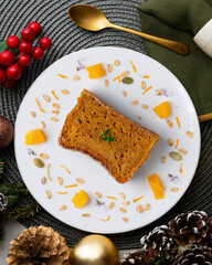 Delicious vegan carrot and tangerine sponge cake with ground almonds. Christmas food served on a table decorated with Christmas motifs.