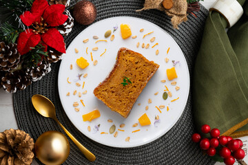 Delicious vegan carrot and tangerine sponge cake with ground almonds. Christmas food served on a table decorated with Christmas motifs.
